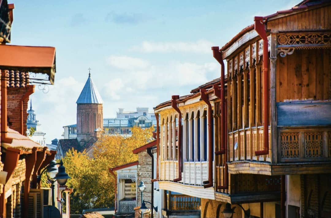 Telavi'de eski bir sokakta oymalı ahşap balkonlar, arkada kilise kubbesi